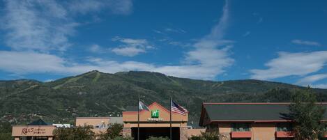 A Holiday Inn with a mountain backdrop, a Rex's American Grill & Bar, and a parking lot.