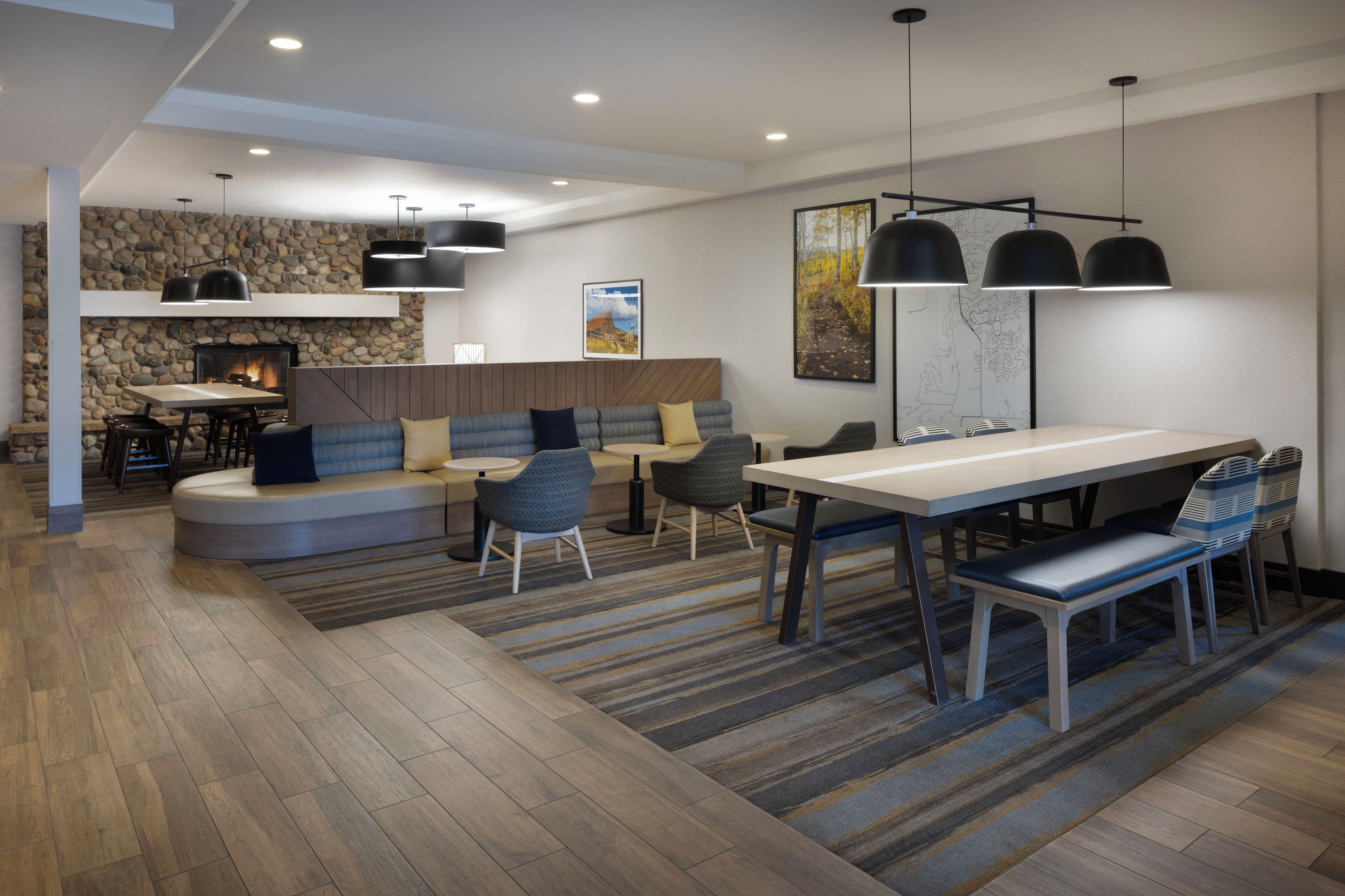 A modern interior with a stone wall, a fireplace, a dining area, and a seating area with sofas and chairs.