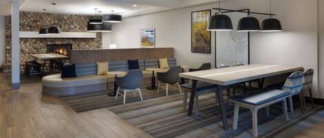 Een modern interieur met een stenen muur, een open haard, een eethoek en een zithoek met banken en stoelen.