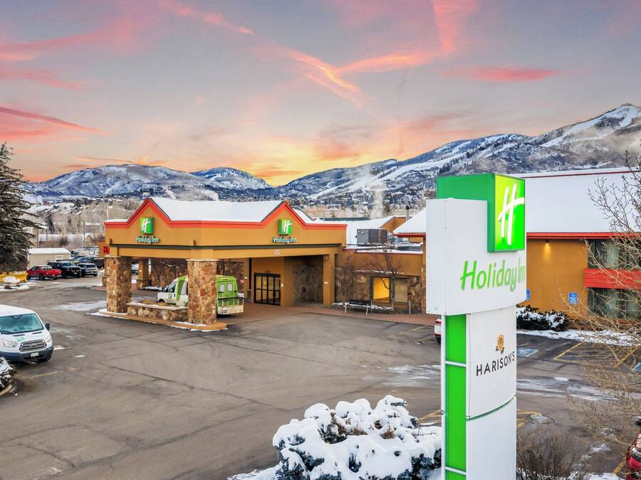 Een Holiday Inn Express met een tankstation, parkeerplaats en bergen op de achtergrond.