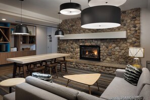 A modern living room with a stone fireplace, wooden furniture, and pendant lighting.