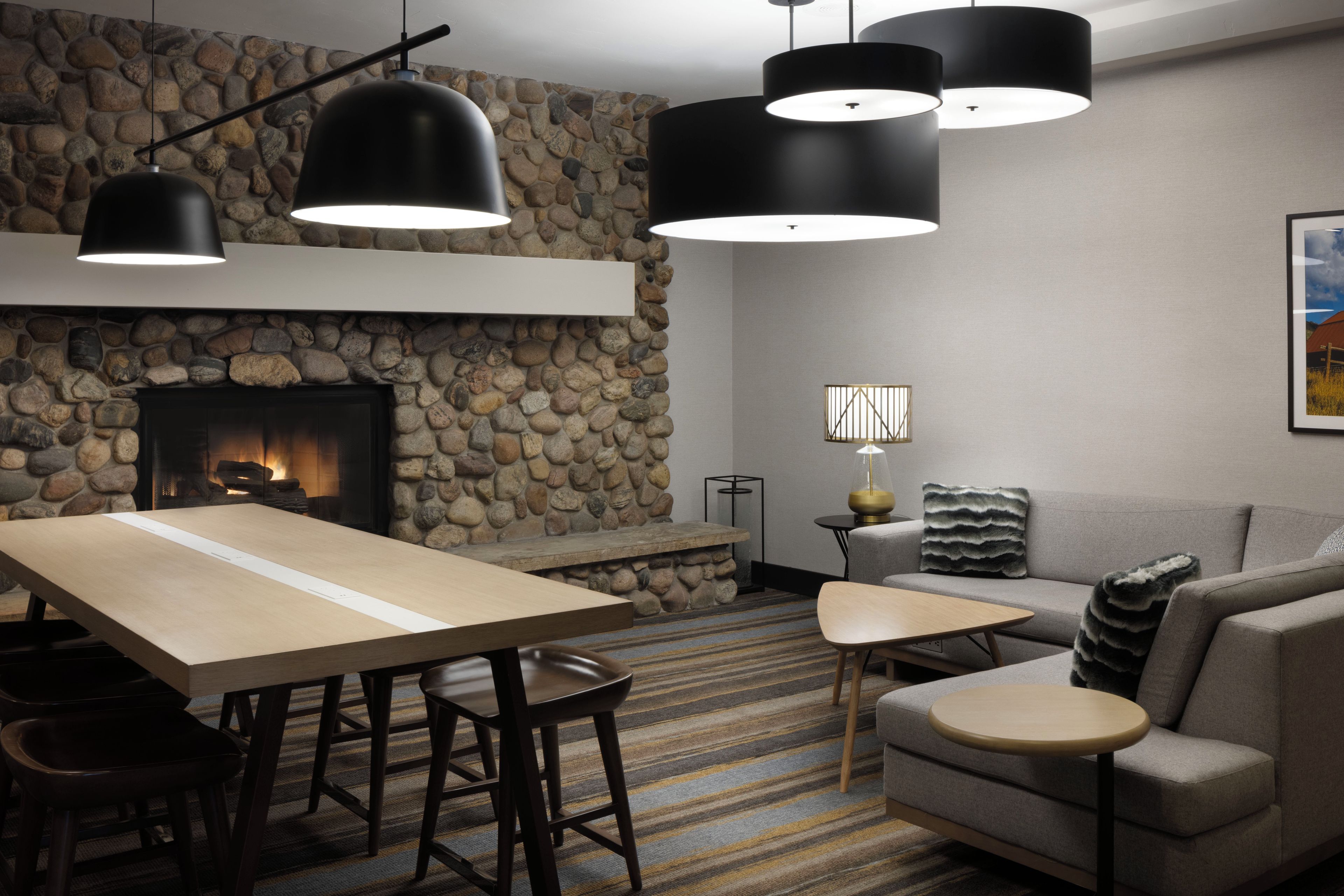 Ein modernes Wohnzimmer mit Steinwand, Kamin und Essbereich mit Tisch und Stühlen.