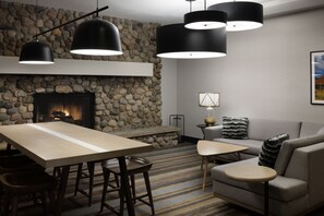 A modern living room with a stone fireplace, a wooden dining table, and a sofa.