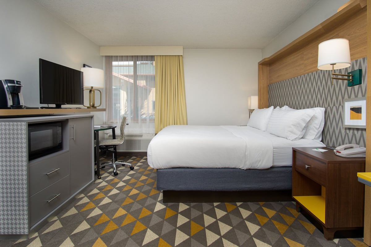 Habitación de hotel con cama, escritorio y kitchenette.