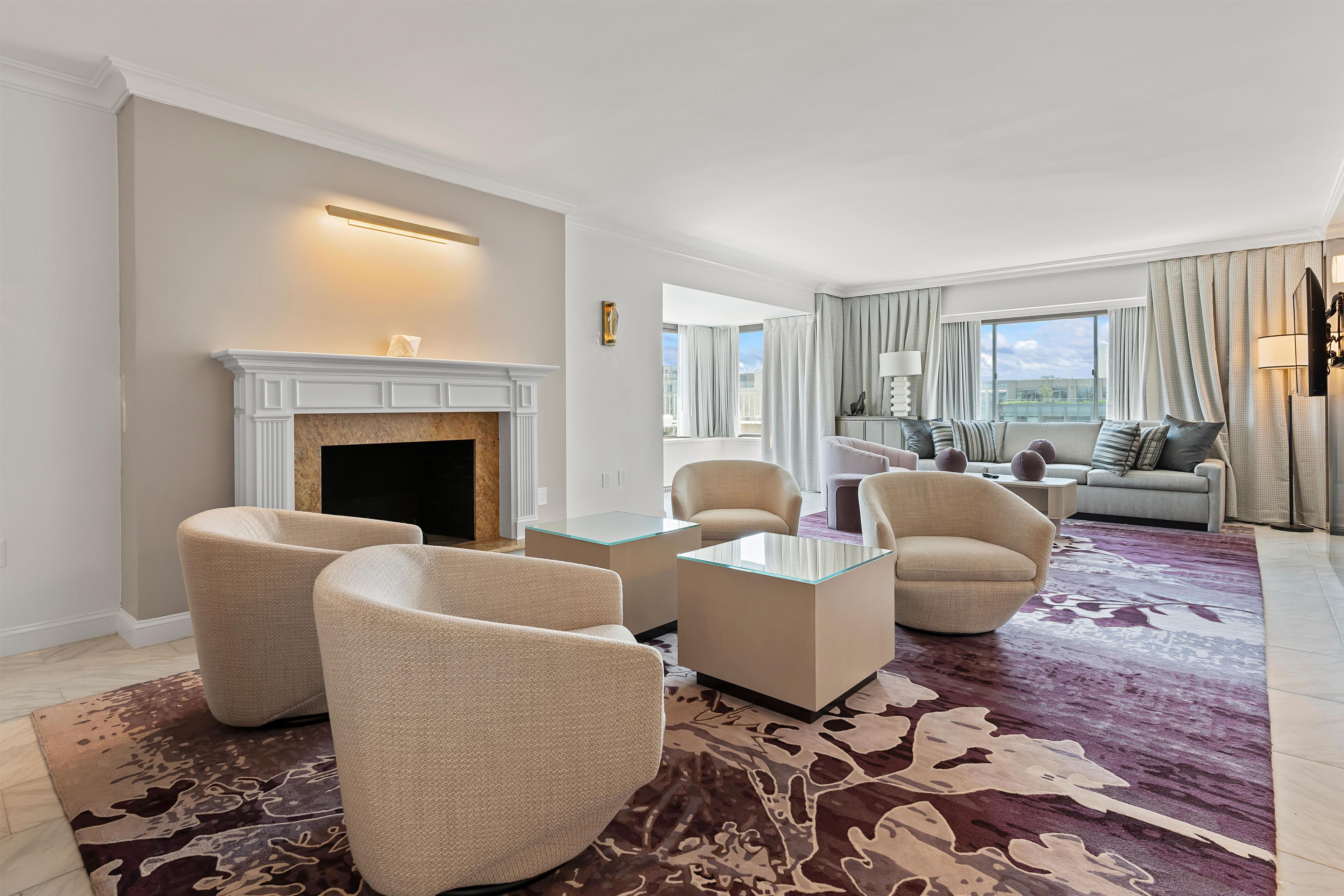 A modern living room with a fireplace, comfortable seating, and a view of the city.