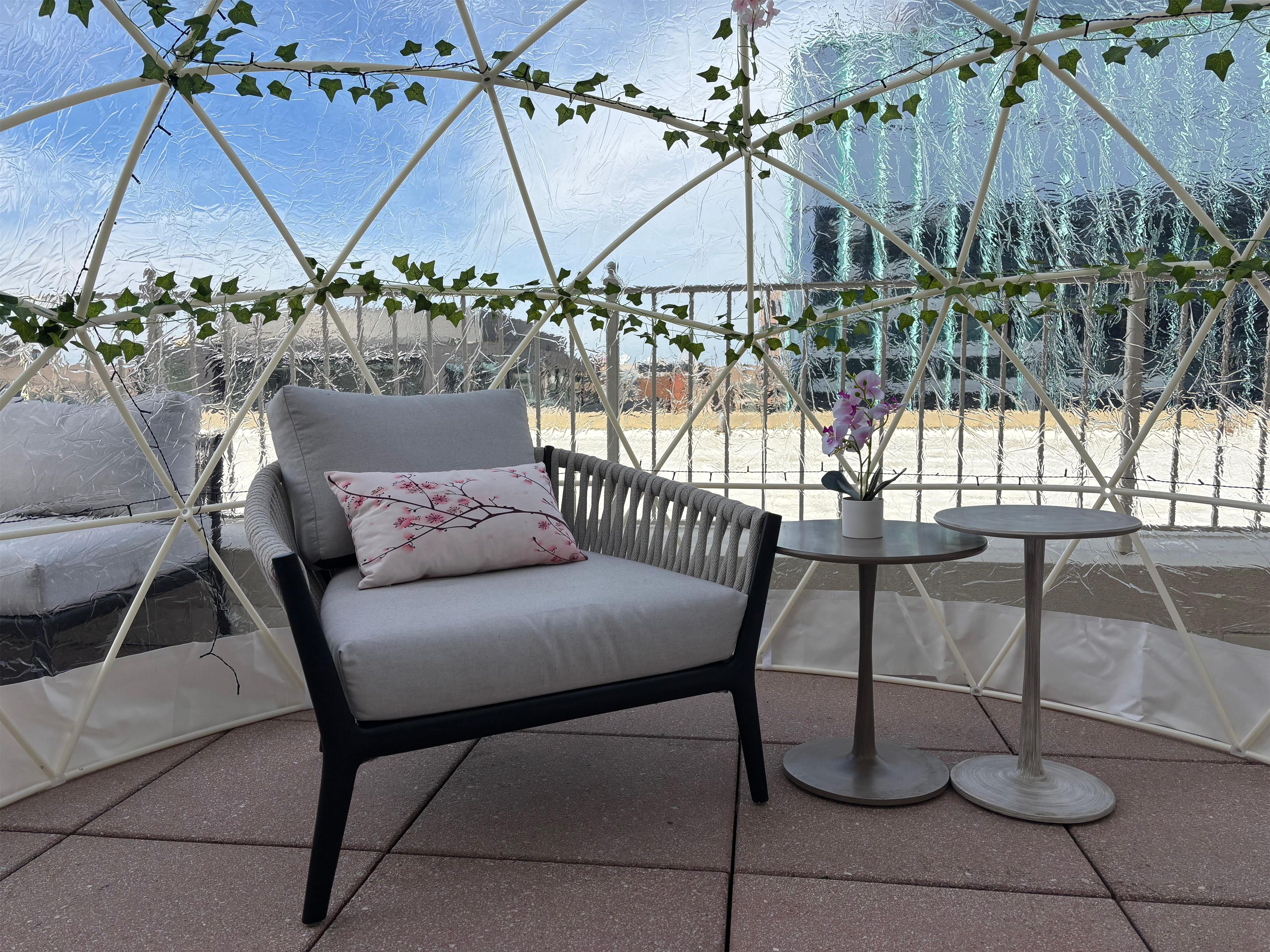 A chair with a cushion and a small table with a potted plant.