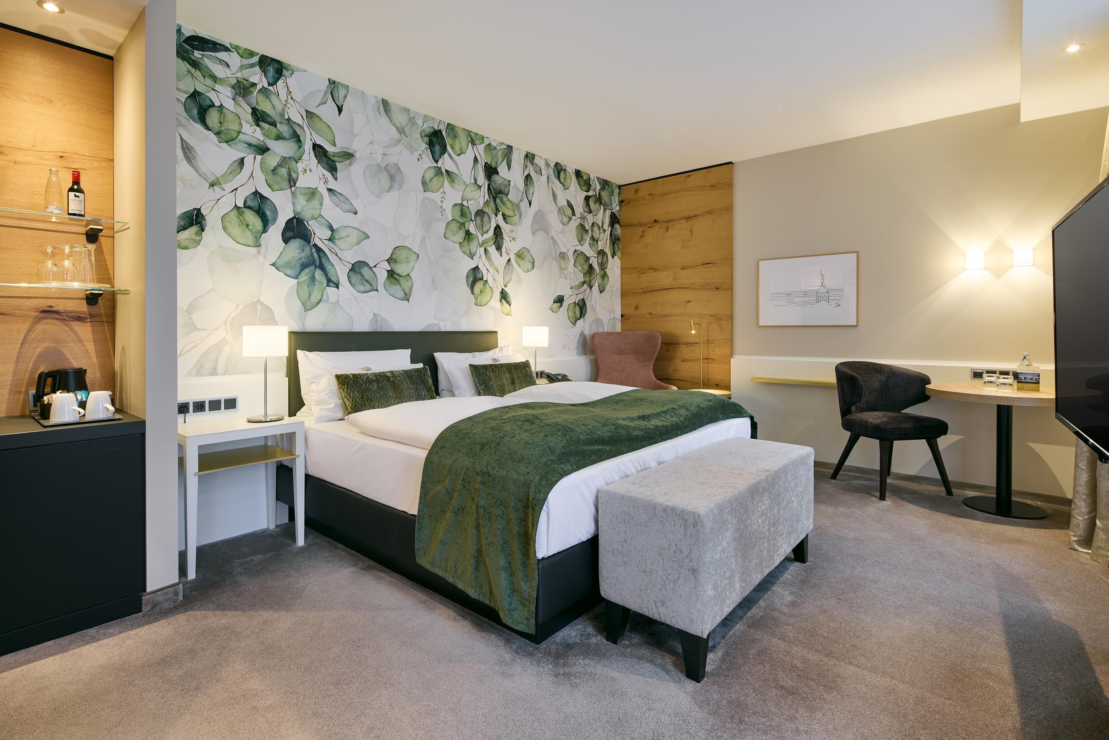 Ein modernes Hotelzimmer mit einem großen Bett, Nachttischen, einem Schreibtisch und einem Fernseher.