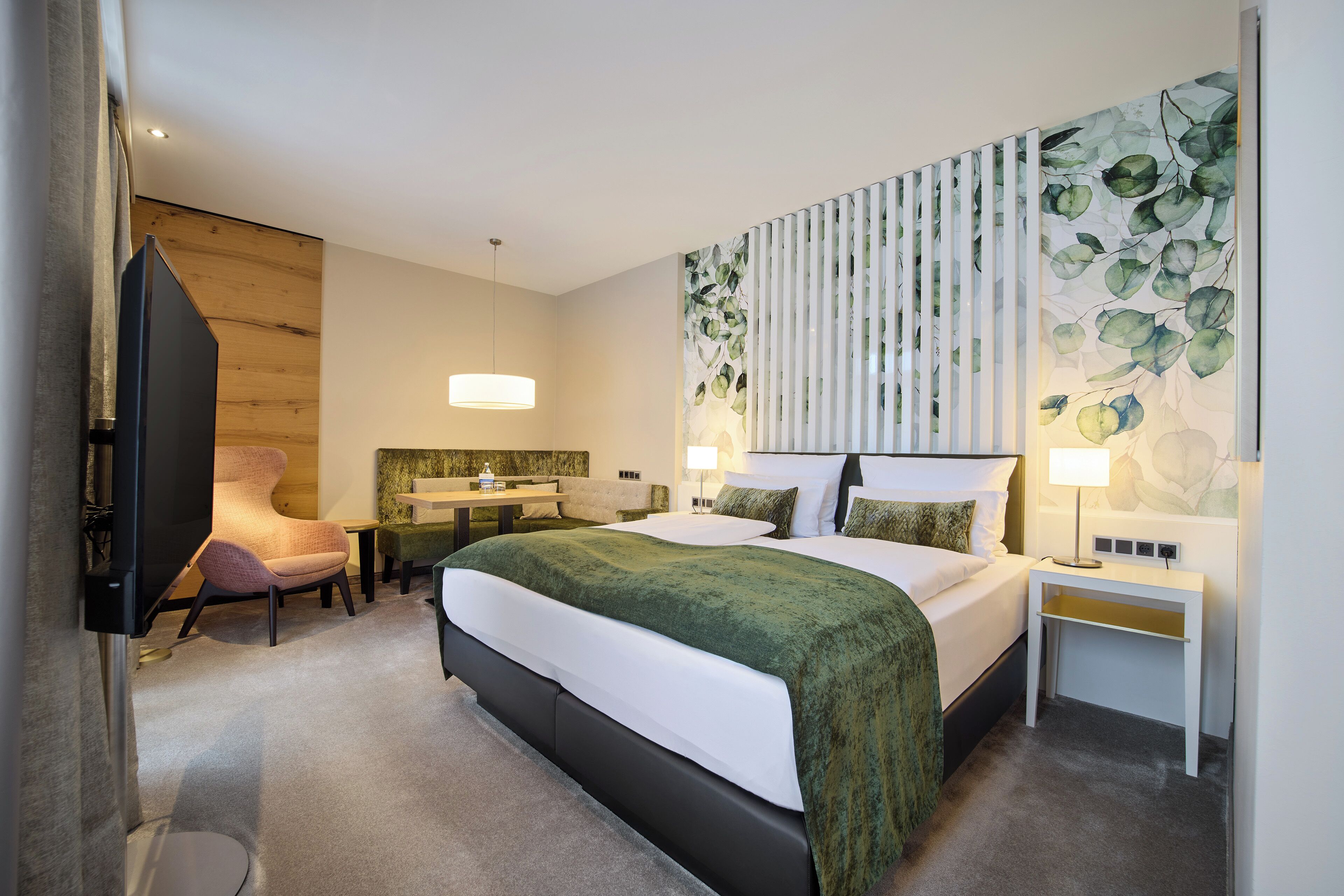 Et moderne hotelværelse med seng, sengeborde, skrivebord, stol og fjernsyn.