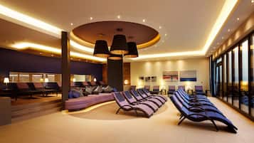A modern lounge area with reclining chairs, a central column, and a ceiling with recessed lighting.