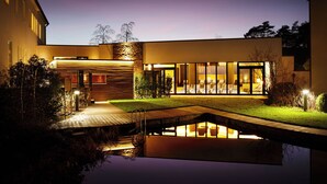 A modern house with a pool, a covered patio, and a well-lit interior. - Best Western Premier Park Hotel and Spa (Bad Lippspringe)