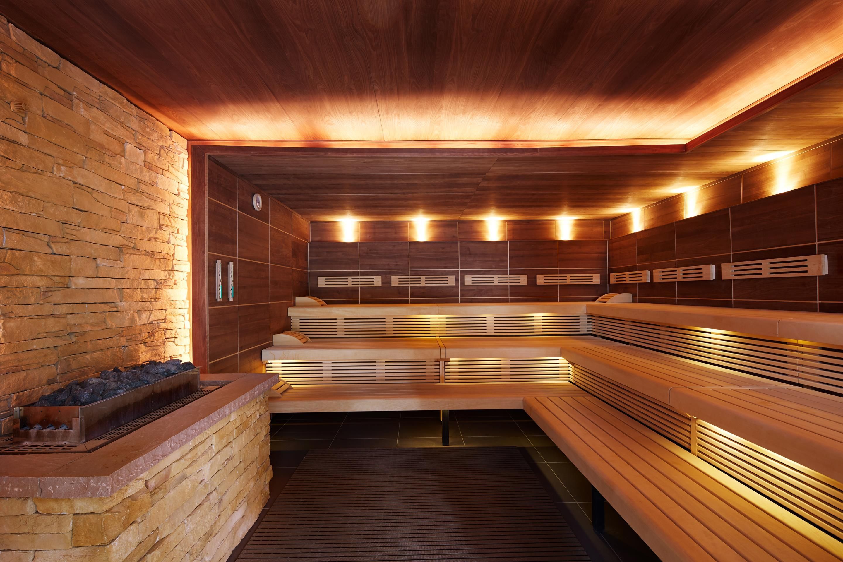 A sauna with wooden benches and a stone wall.