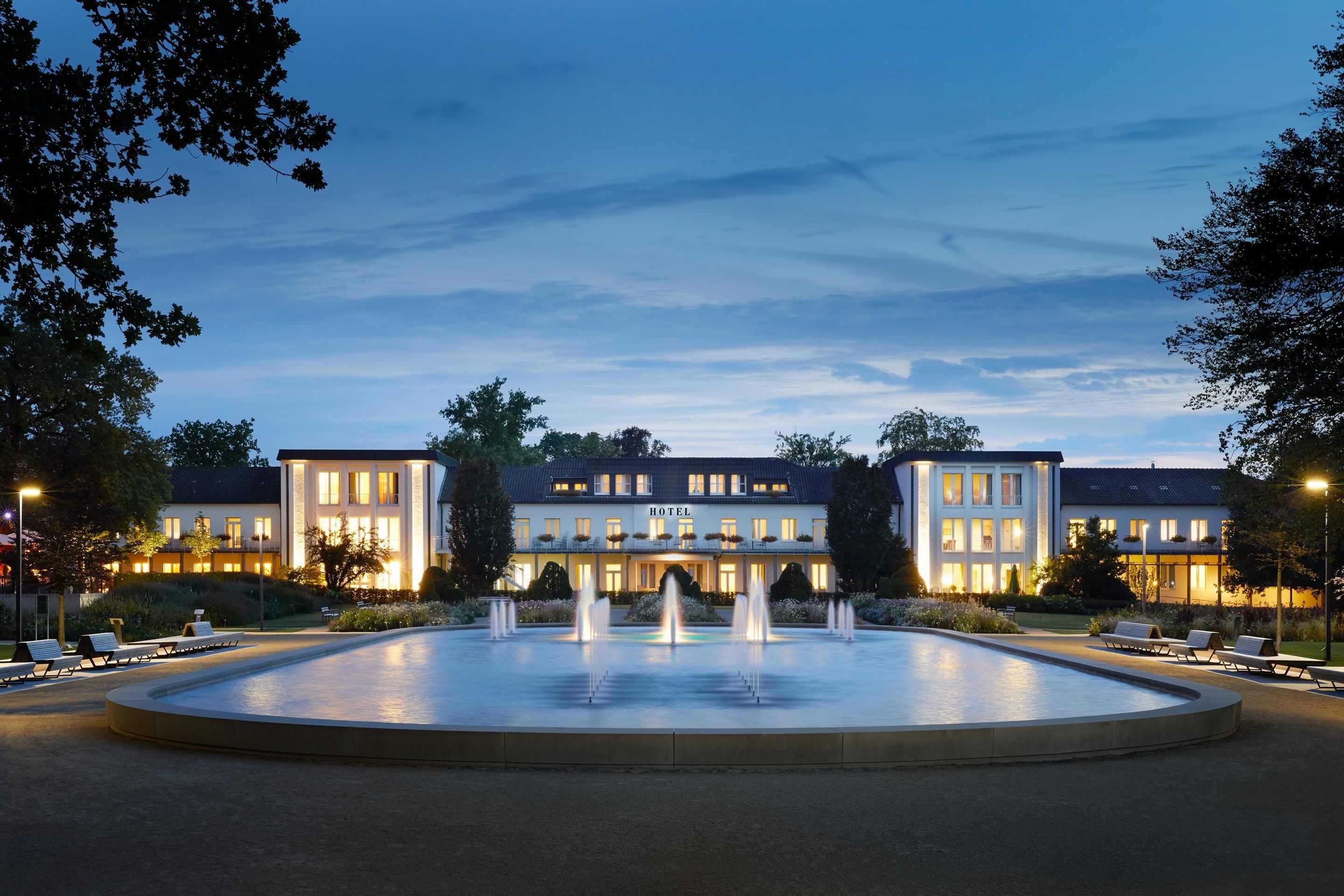 A hotel with a central fountain, multiple balconies, and a well-lit facade.
