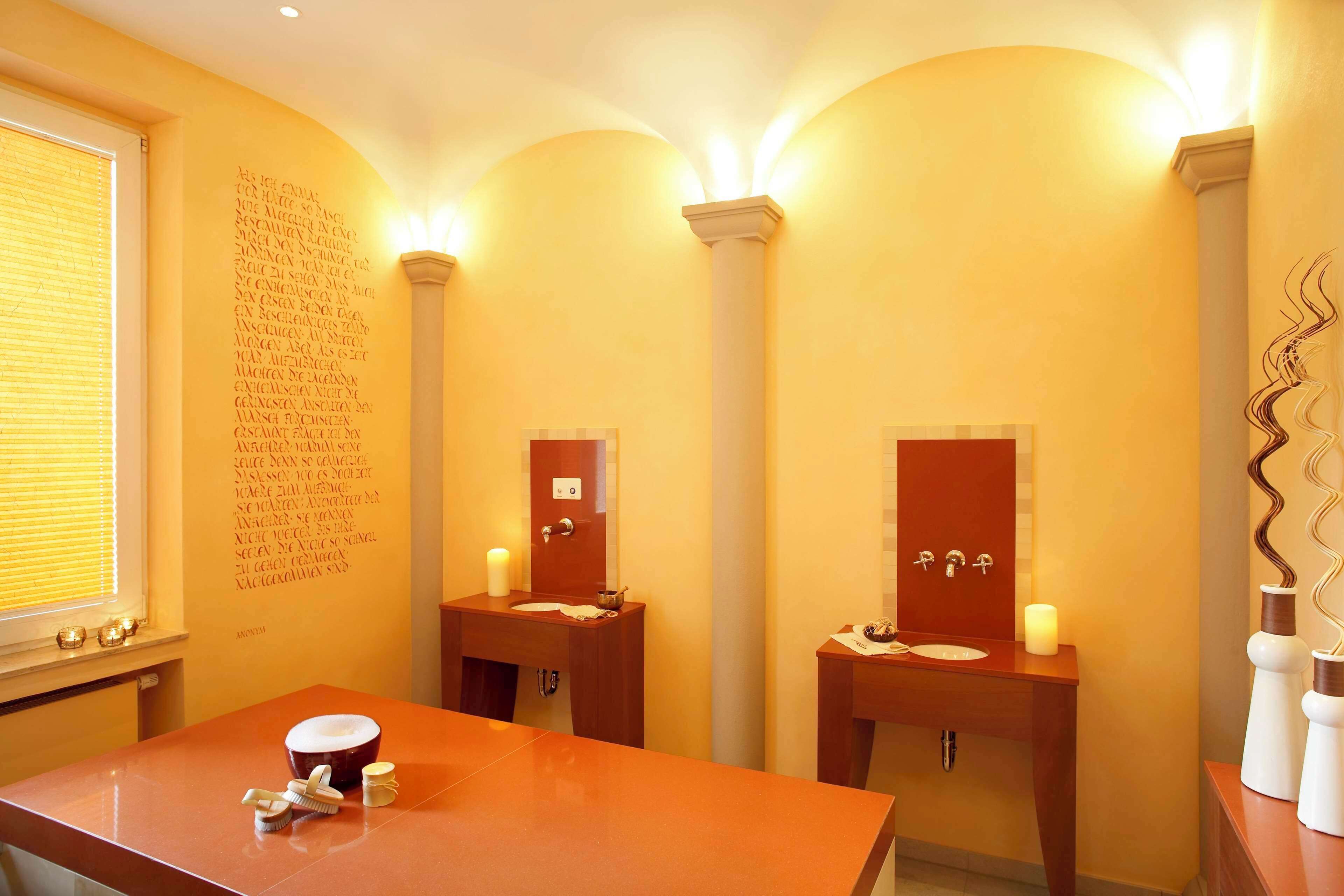 A bathroom with two sinks, a mirror above each, and a large window with blinds.