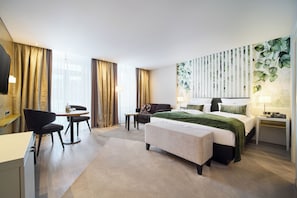 A hotel room with a bed, bedside table, lamp, chair, desk, and a large window with curtains. - Best Western Premier Park Hotel and Spa (Bad Lippspringe)