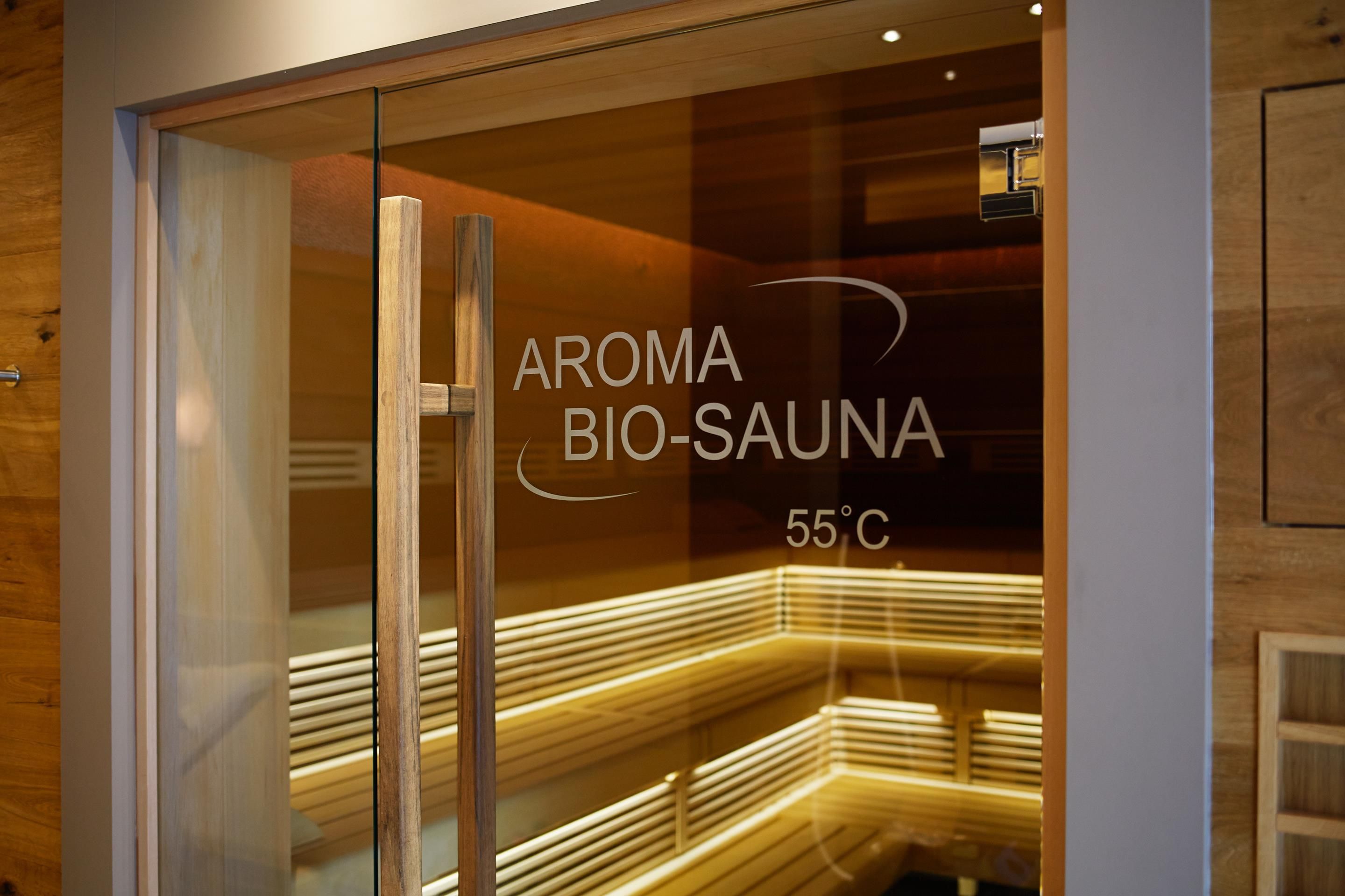 Eine Glastür mit dem Schriftzug 'AROMA BIO-SAUNA 55°C', der auf eine Sauna hinweist.