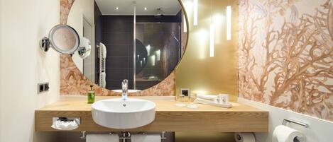 A modern bathroom with a round mirror, a sink, and a towel rack.