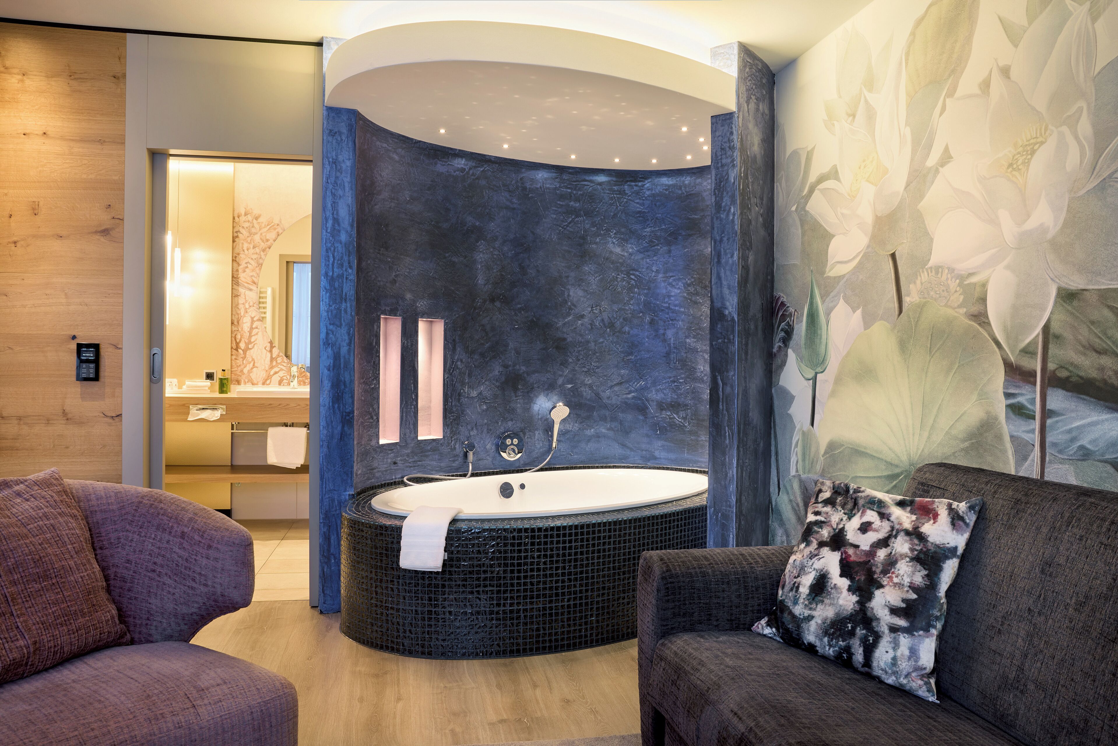 Un baño moderno con una bañera independiente, un tocador de madera y un gran mural floral.