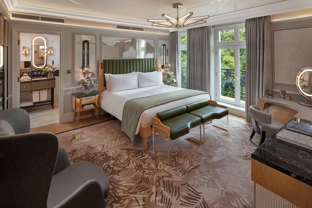 Ein geräumiges Hotelzimmer mit einem großen Bett, einer Sitzecke, einem Schreibtisch und Blick ins Freie.