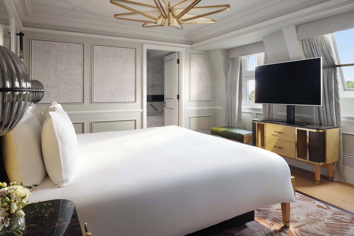 Ein geräumiges Schlafzimmer mit einem großen Bett, einem Fernseher und einem durchgegangenen Tür erkennbaren Badezimmer.