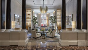 A spacious lobby with a central seating area, large columns, and a chandelier.