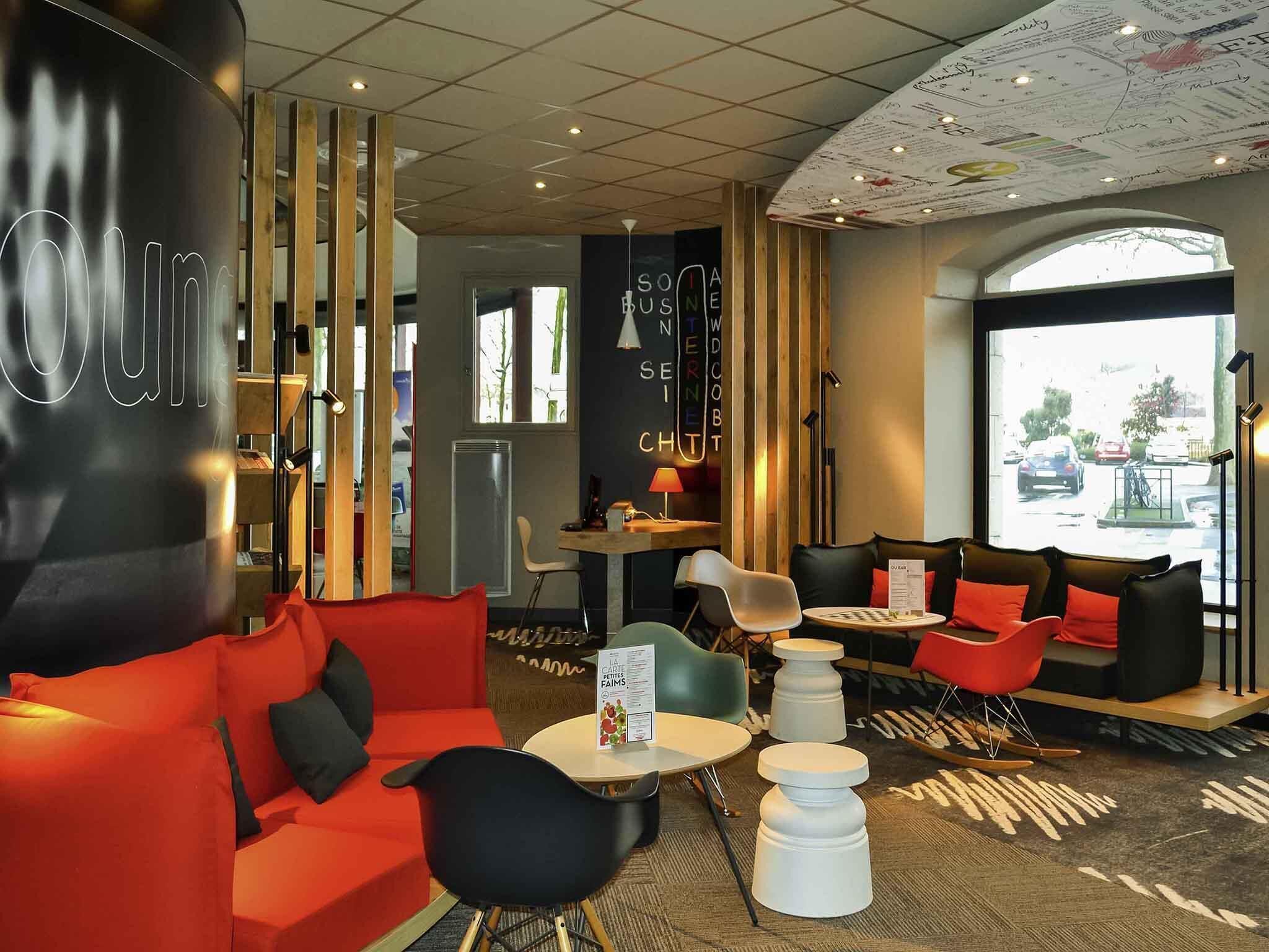 Un área de estar moderna con un sofá rojo, sillas negras y una mesa pequeña con un menú.