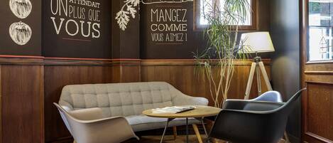 A cozy interior with a sofa, two chairs, a small table, and decorative wall art.