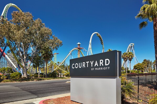A sign for 'Courtyard by Marriott' with roller coaster tracks in the background.