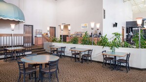 A restaurant with a patterned carpet, tables and chairs, a staircase, and a counter with a sign. - Days Inn by Wyndham Kirksville (Kirksville)