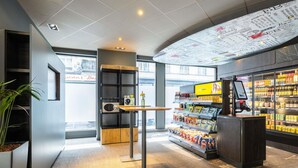 Un interior moderno con una barra de café, estantes llenos de refrigerios y un amplio ventanal.