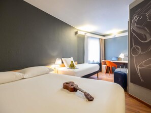 A hotel room with two beds, a desk, a chair, a guitar, and a wall with a chalk drawing.