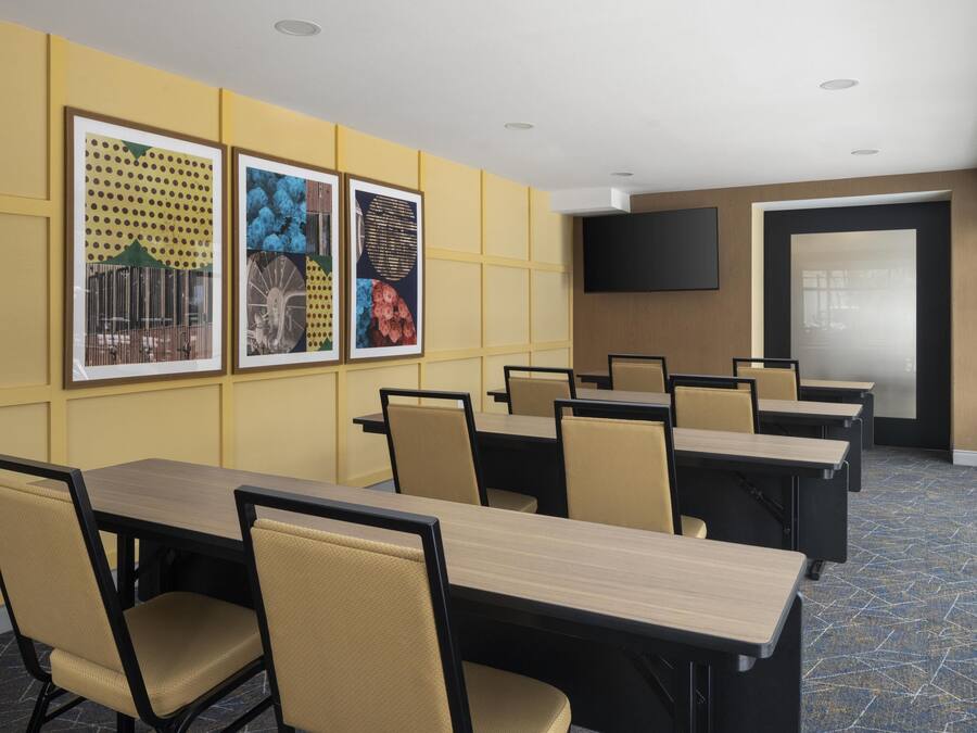 A conference room with multiple tables and chairs, framed artwork on the walls, and a flat-screen TV.