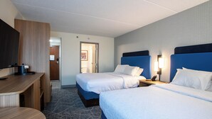Ein Hotelzimmer mit zwei Betten, einem Schreibtisch und einem Fernseher.