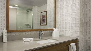 A bathroom with a large mirror, a sink, a towel rack, and a framed picture on the wall.
