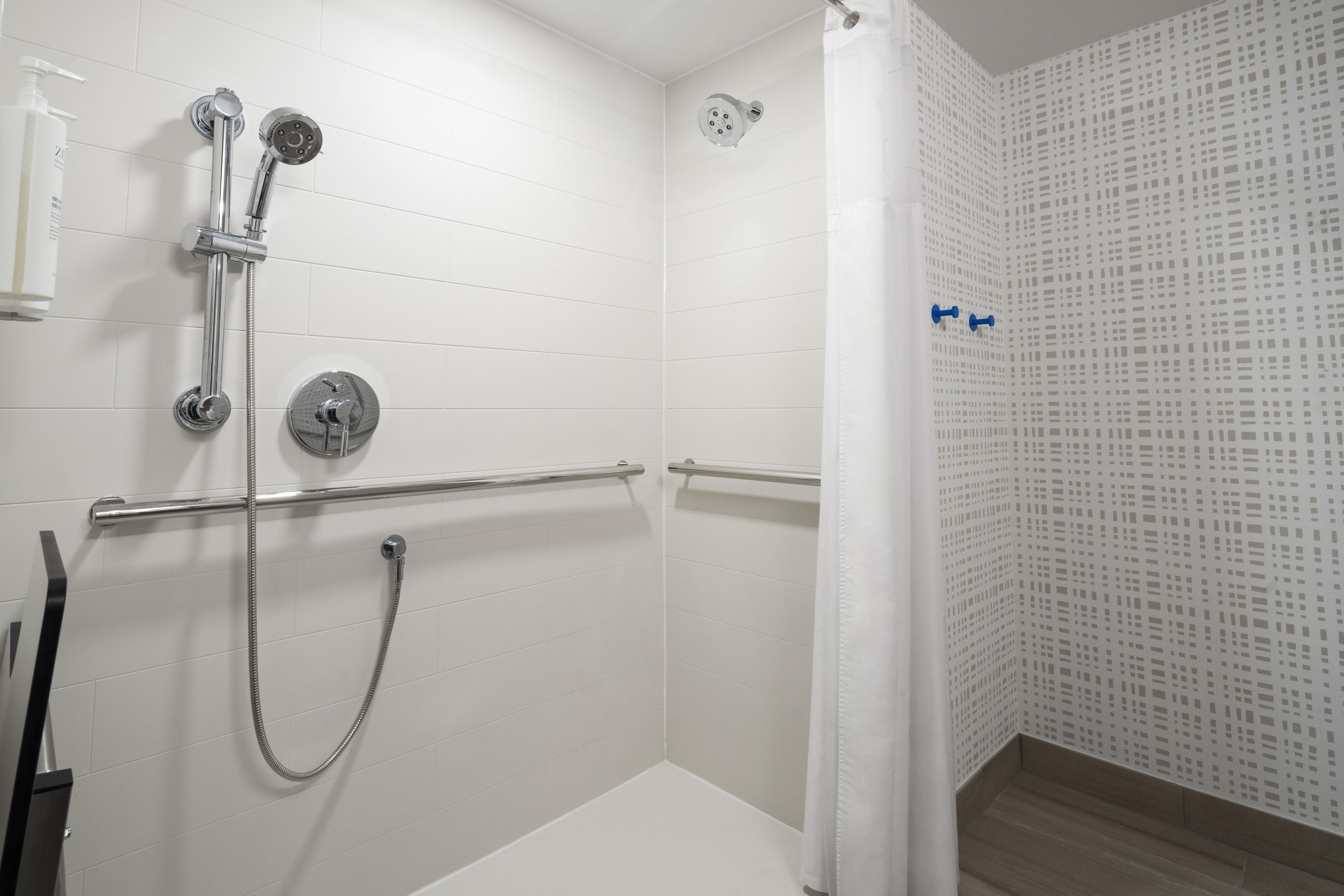 A shower area with a handheld showerhead, a wall-mounted showerhead, and a handheld shower hose.