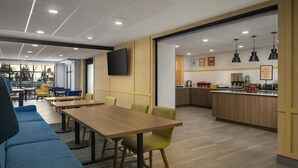 Ein moderner Essbereich mit Holztischen und -stühlen, eine Küchenzeile mit einer Frühstückstheke und ein großes Fenster, das für natürliches Licht sorgt.