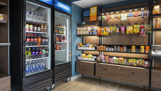 Ein Getränkeautomat mit verschiedenen Getränken und Snacks, darunter Wasserflaschen, Limonaden und verpackte Snacks.