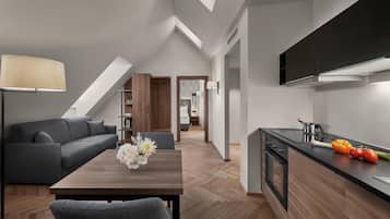 A modern kitchen with a dining area, featuring a wooden herringbone floor, a dark countertop, and a built-in oven.