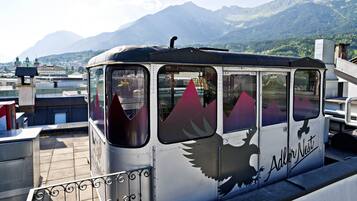 A stationary train with a distinctive eagle design and the name 'Adler Nest' on its side, set against a mountainous backdrop.