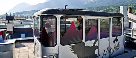 A stationary train with a distinctive eagle design and the name 'Adler Nest' on its side, set against a mountainous backdrop.