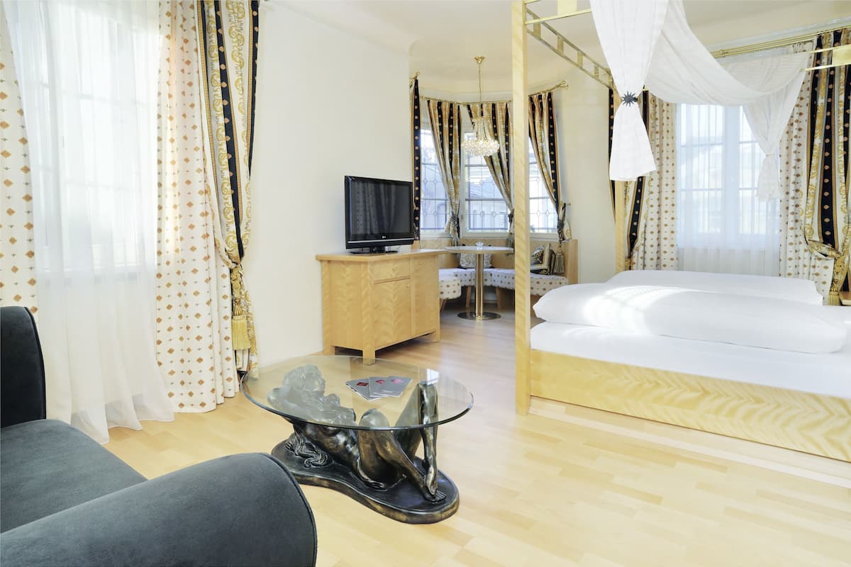 Ein Hotelzimmer mit einem Bett, einem Fernseher, einem Glastisch und Vorhängen.