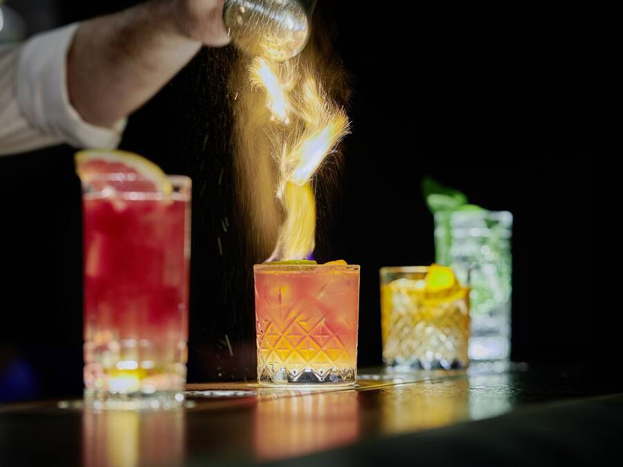 Una persona sirviendo una bebida en un vaso con efecto de llama.