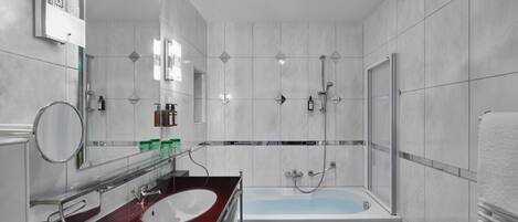 Un baño moderno con tocador rojo, bañera blanca y cabina de ducha de vidrio.