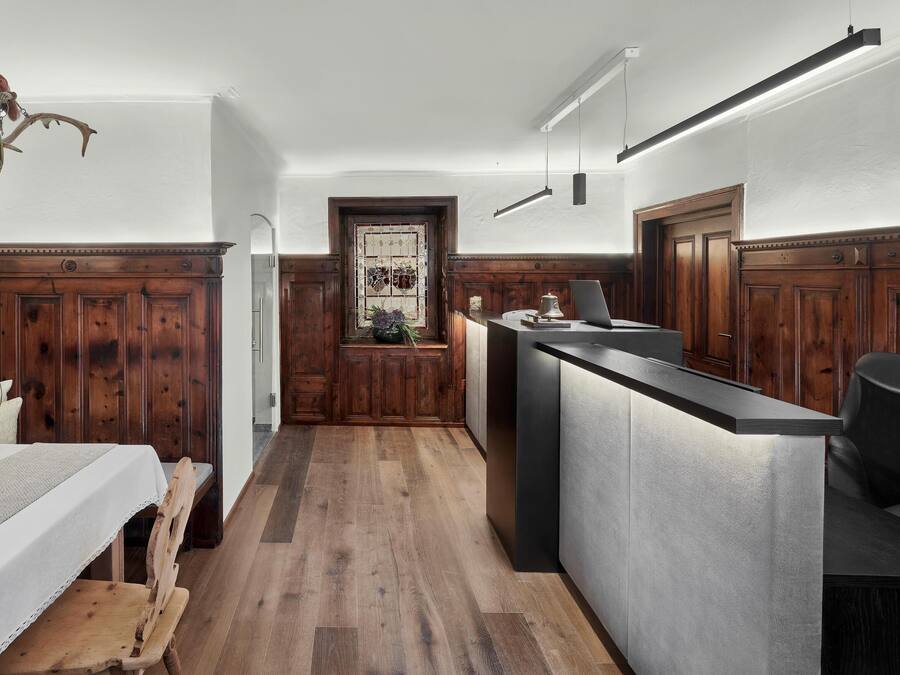 A modern kitchen with wooden paneling, a central island, and a dining area with a table set for four.