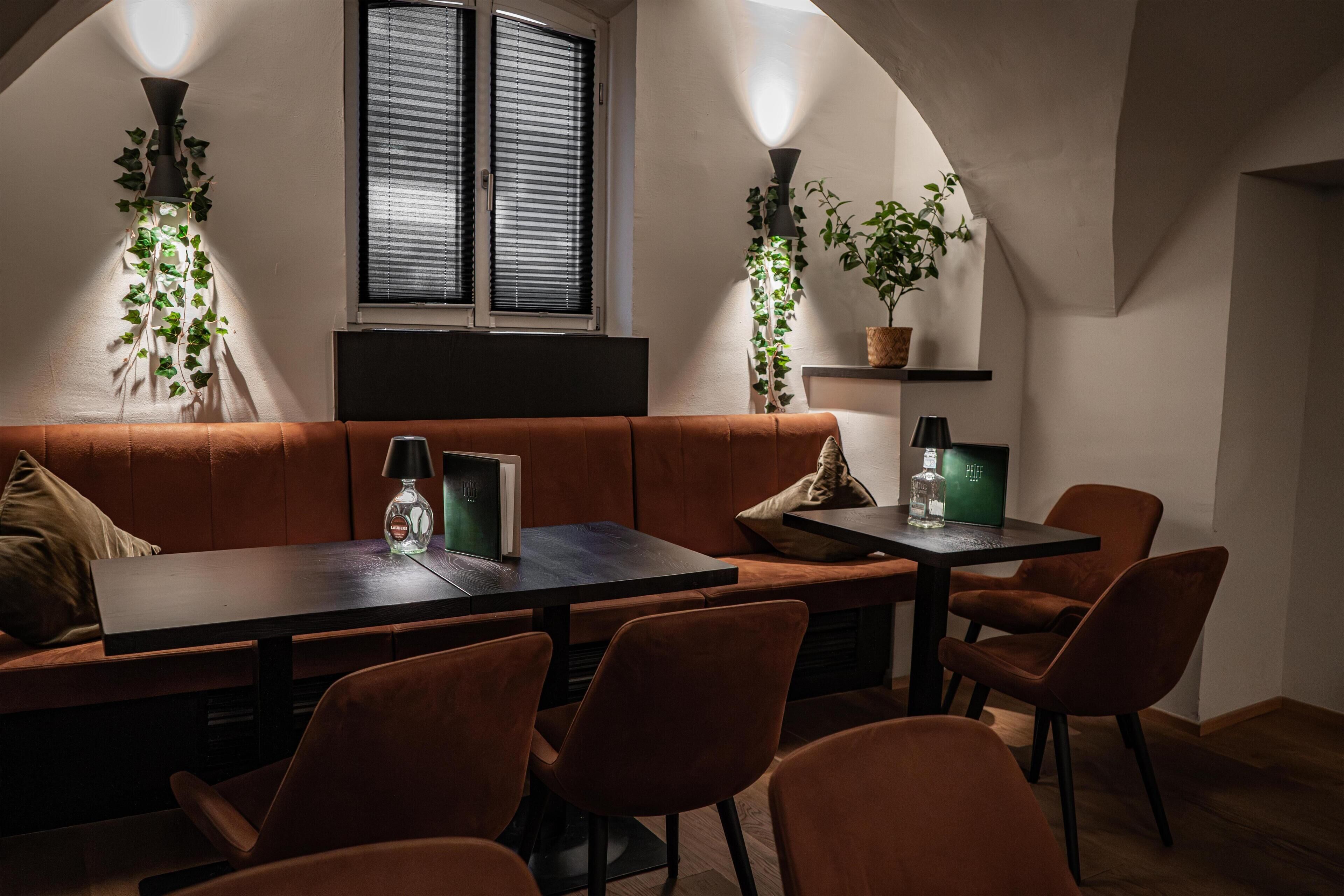A cozy dining area with a wooden table and chairs, a cushioned bench, and potted plants.