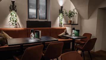 A cozy dining area with a wooden table and chairs, a cushioned bench, and potted plants.