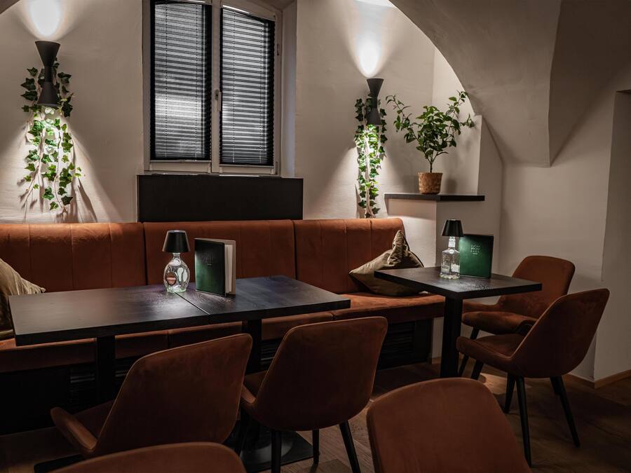 A cozy dining area with a wooden table and chairs, a cushioned bench, and potted plants.