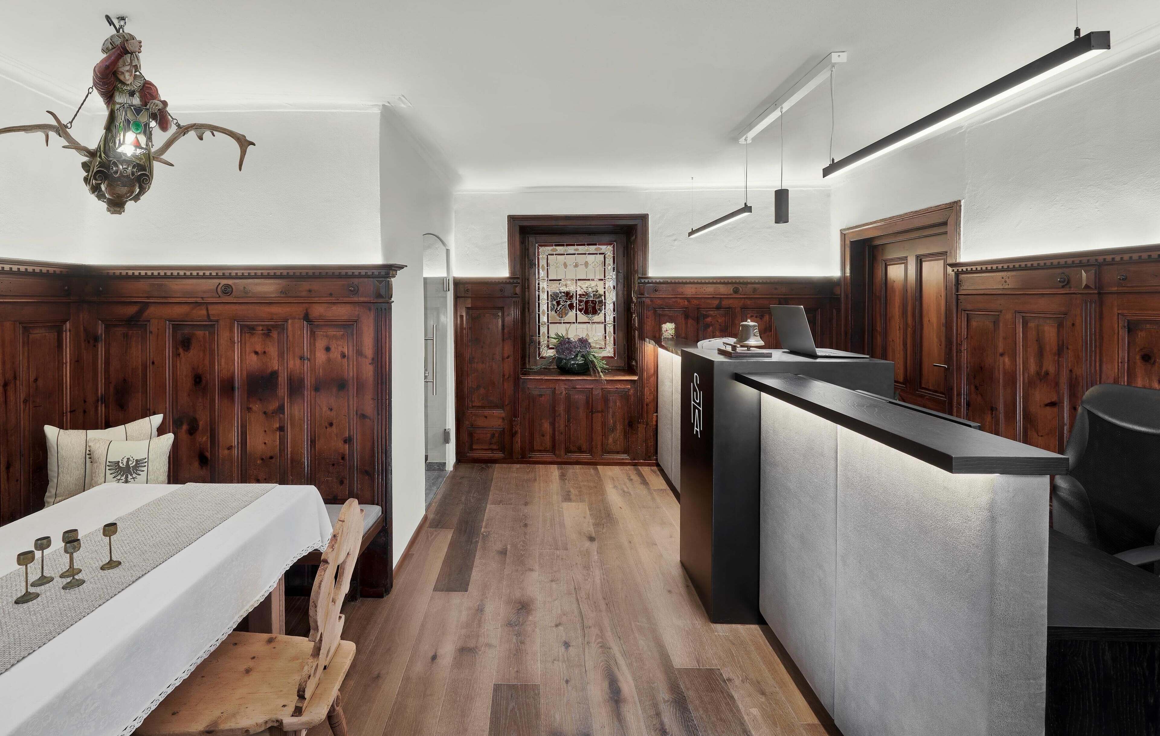 Una cocina con paneles de madera, una mesa de comedor con sillas, una barra y una lámpara de araña.