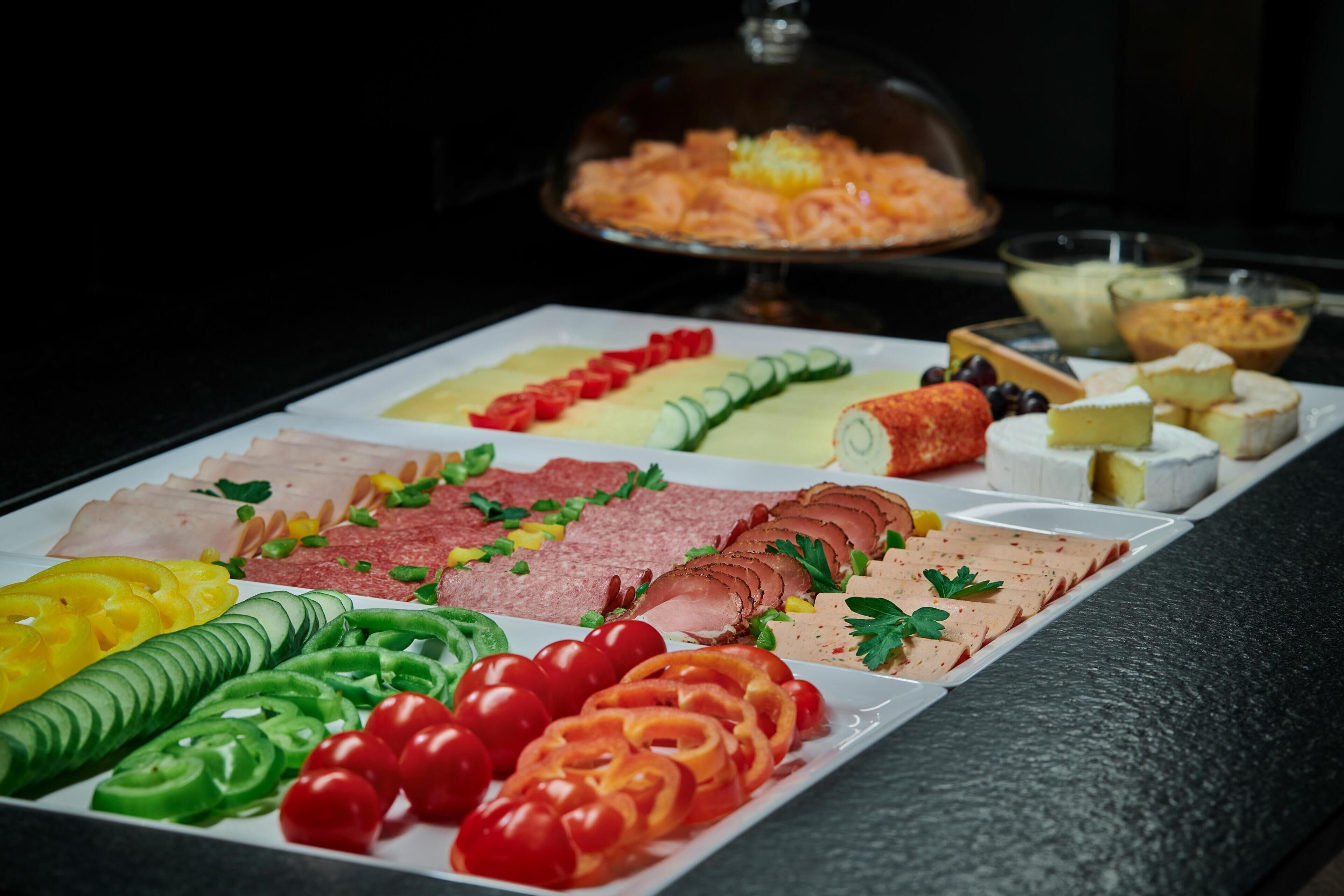 Ein reichhaltiges Buffet mit verschiedenen Speisen, darunter Aufschnitt, Käse und Gemüse.