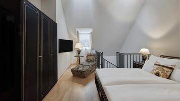 A bedroom with a bed, a chair, a wardrobe, a TV, and a window.