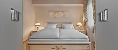 A neatly made bed with a decorative headboard, two bedside lamps, and a wall-mounted artwork above.